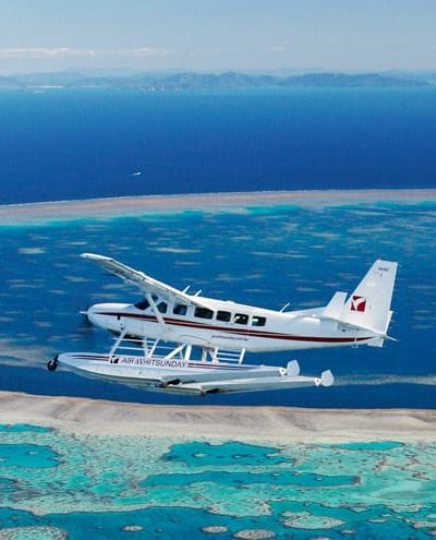 a small plane flying over a large body of water.