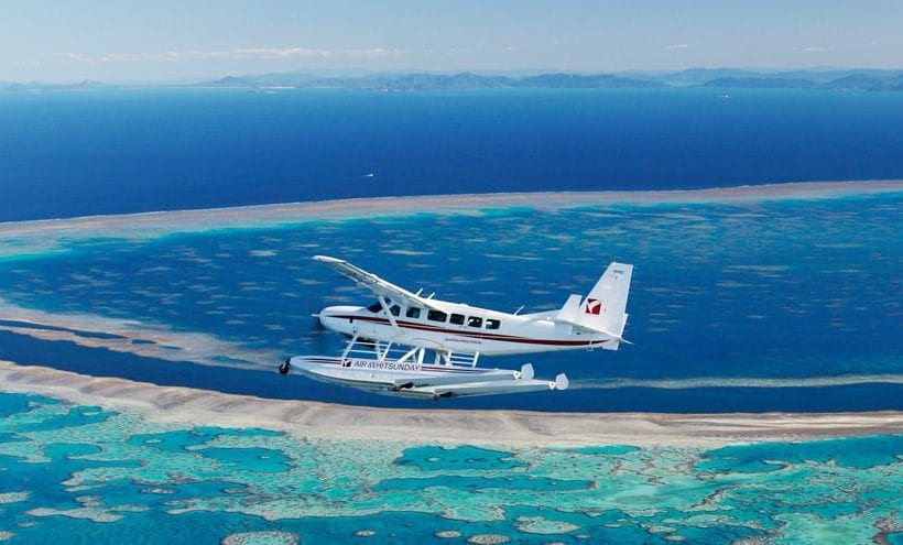 a small plane flying over a large body of water.