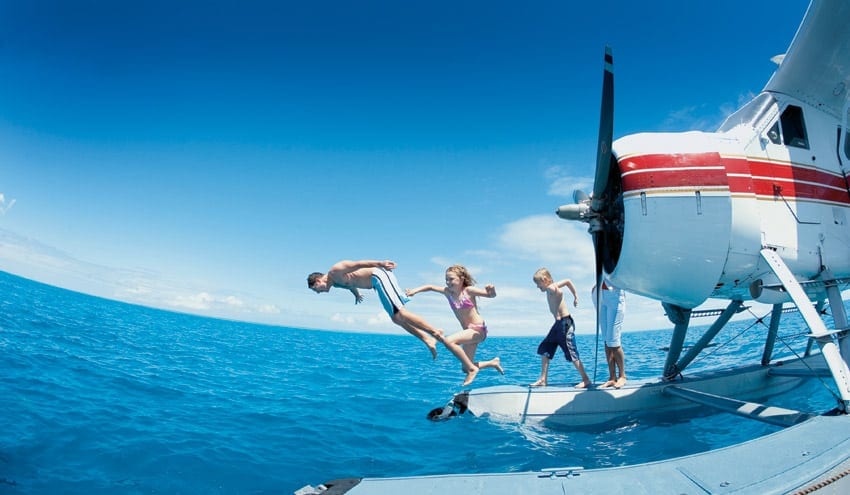 a group of people jumping off a plane into the ocean.
