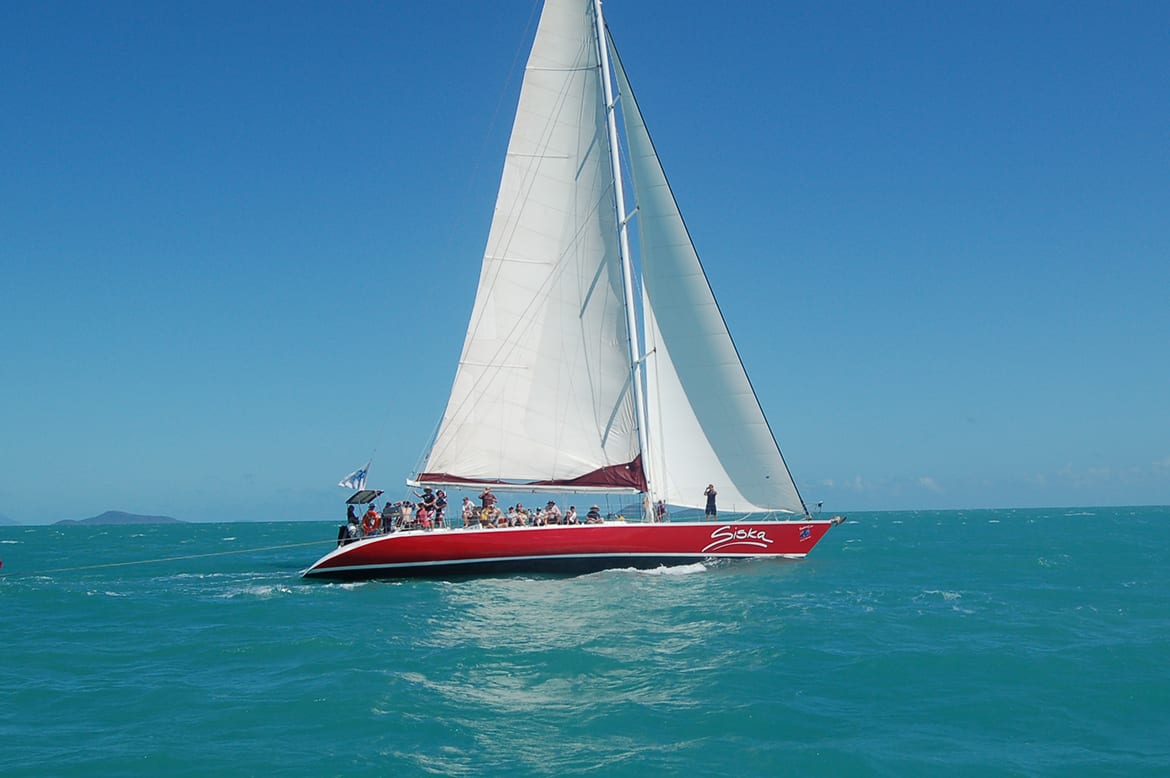 a red sailboat with white sails in the ocean.